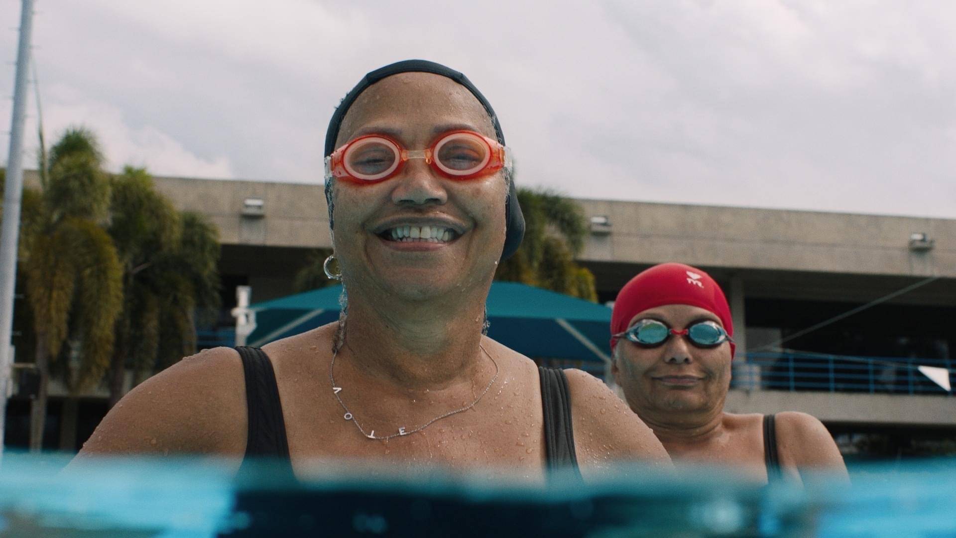 two older women in pool with goggles and swim caps on